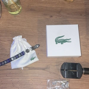 Silverfärgat armband från Lacoste - Snyggt armband från Lacoste i silverfärgad metall med fyrkantiga länkar och diskret Lacoste-logga. Kommer med originalpåse, ask och extra länkar samt verktyg för justering. Perfekt accessoar för dig som gillar stilrena detaljer.