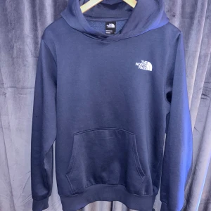 North face hoodie  - Snygg mörkblå hoodie från The North Face med vit logga på bröstet. Klassisk känguruficka framtill och huva. Perfekt för chill dagar eller när du vill ha en enkel och stilren look. Mjuk och skön i bomullsmix.