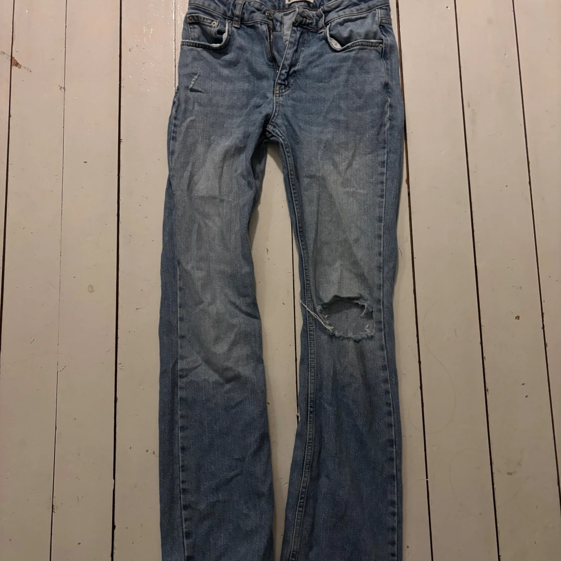 Blå jeans med hål på knät