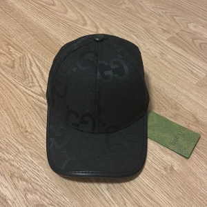 Svart keps Jumbo-stil  - Säljer en snygg svart keps i Jumbo-stil. Klassisk böjd skärm med svart kant i läder och justerbar rem baktill. Hör av er vid intresse!