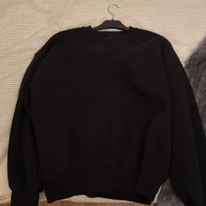 Svart sweatshirt från Sweet SKTBS - Svart sweatshirt från Sweet SKTBS med stor vit textprint på ryggen. Tröjan har rund hals, långa ärmar och en loose passform. Tillverkad i mjuk bomull, perfekt för en chill streetwear-look. Ganska oversized 