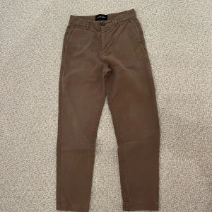 Bruna/beiga chinos från A Day's March - Snygga bruna/beiga chinos från A Day's March med klassisk rak passform och midwaist. Byxorna har sidfickor fram, två bakfickor med knapp och bälteshällor. Materialet är mjuk bomull.                    HELT UTSÅLDA och går inte längre att köpa, BUDA!! Miller-modellen, NYPRIS: 1295