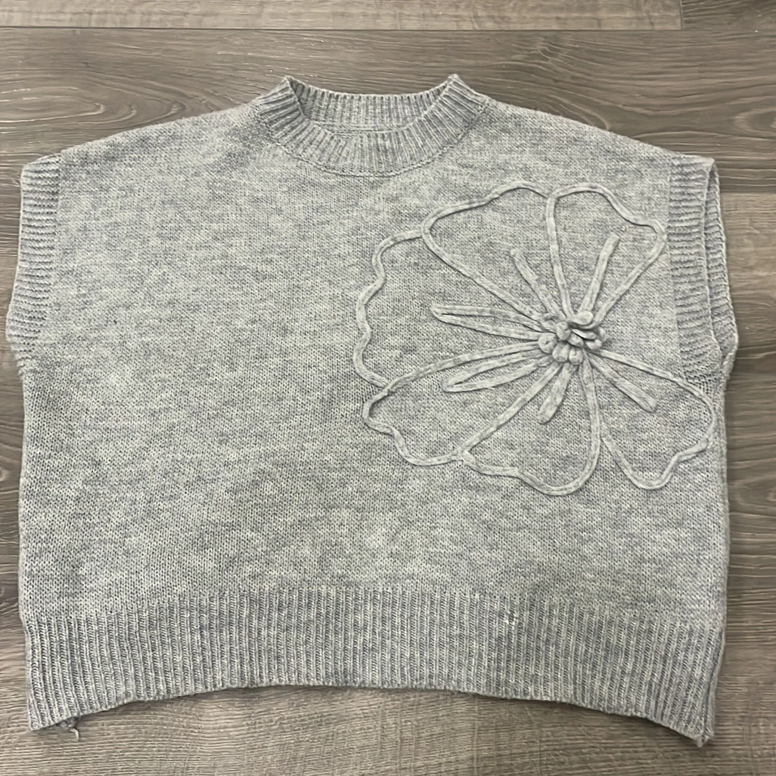 Grå stickad väst med blomdetalj
