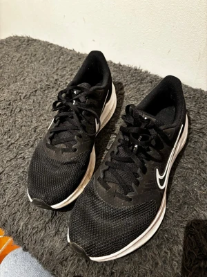 Nike löparskor – perfekta för vinterträning inomhus & milda dagar - Säljer ett par svarta Nike löparskor i bra begagnat skick. Skorna är lätta, bekväma och ger bra dämpning – perfekta för vinterträning på gym, löpband eller promenader närSäljer ett par svarta Nike löparskor i bra begagnat skick. Skorna är lätta, bekväma och ger bra dämpning – perfekta för vinterträning på gym, löpband eller promenader när vädret tillåter.  ✔ Bekväm passform ✔ Stabil sula med bra stöd ✔ Andningsbart material ✔ Passar både träning och vardag  Normalt slitage syns på sulan (se bild