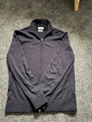 Helzip från these  glory days  - Klassisk kofta med hel dragkedja framtill och hög krage. Tillverkad i mjuk merinoull , perfekt för lager på lager under kyligare dagar. Långärmad och enkel design som funkar till det mesta. Hör av dig vid frågor!