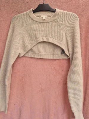 Beige croppad stickad tröja H&M - Beige croppad stickad tröja från H&M i storlek XS. Lång ärm, rund halsringning och ribbad struktur. Perfekt för lager på lager..