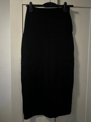 Svart långkjol från H&M, storlek L - Enkel och stilren svart långkjol i storlek L. Kjolen har rak passform och är tillverkad i ett mjukt tyg som känns bekvämt. 