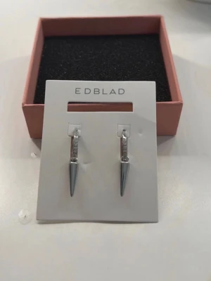 Edblad Peak Hoops Sparkle Steel - Edblad Peak Hoops Sparkle Steel i rostfritt stål. Örhängena är helt nya och aldrig använda. De ligger i originalförpackning och lådan ingår. Modellen har silvriga, gnistrande stenar. Passar till både vardag och fest. I helt nytt skick.