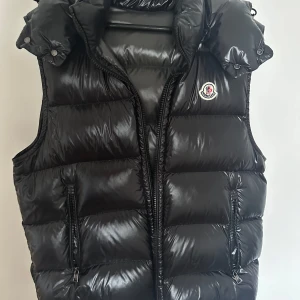 Moncler Bormes Väst - Säljer en äkta Moncler Bormes dunväst i klassisk svart färg. Västen är i nyskick och knappt använd. Den är lätt, varm och perfekt för både höst, vinter och vår. Västen är Köpt för 14 000 men säljer den nu för 8 000 priset kan diskuteras vid snabb affär! Vid intresse samt fler bilder är det bara att höra av sig. Fraktar snabbt! (OBS storlekn är 4 men denna väst är väldigt liten i storlek så den passar dem som använder M/L i storlek)
