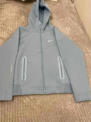 Nike Tech Fleece hoodie / nocta - Nike Tech Fleece zip hoodie (Nike Trail) Stilren och funktionell hoodie i mjukt Tech Fleece-material. Lätt men varm, med huva, hel dragkedja och två dragkedjefickor. Perfekt för vardag, träning eller utomhusbruk. Mycket fint skick.