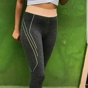 Två par träningstights S-M - Säljer två par snygga träningstights i storlek S-M. Ena paret är mörkgrå med ljusrosa midja och vita linjer längs benen, det andra paret har ett coolt mönster i rosa, grått och svart. Båda är höga i midjan och sitter tight för en sportig look. Säljes 2 par 