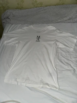 Vit Modern Archive t-shirt Jack & Jones - Snygg vit t-shirt från Jack & Jones Modern Archive med svart tryck på bröstet. Klassisk rund hals och korta ärmar. Tillverkad i mjuk bomull för skön känsla och enkel stil. Perfekt till jeans eller shorts för en clean look.