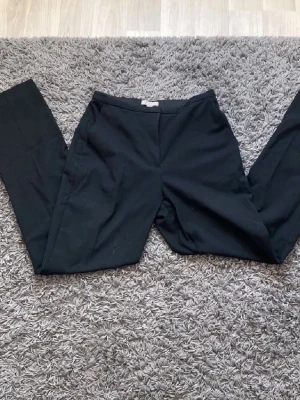Svarta kostymbyxor  - Snygga svarta kostymbyxor med rak passform och diskret dragkedja fram. Klassisk midja och stilren look som passar till allt. Materialet känns mjukt och följsamt, perfekt för dig som gillar en clean och enkel stil.❤️