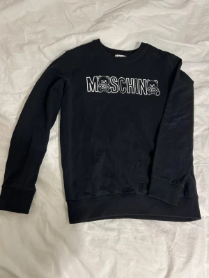 Svart Moschino sweatshirt  - Svart sweatshirt från Moschino med vita konturer och två söta björnar på bröstet. Tröjan har rund hals, ribbade muddar och är långärmad. 