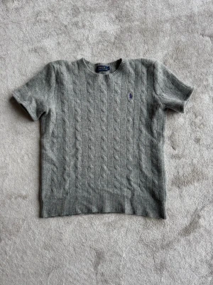 Grå Ralph lauren t-shirt - Jättesnygg grå kabelstickad Ralph lauren t-shirt som tyvärr inte kommer till användning längre😔 90% ull 10% cashmir. Köparen står för frakt