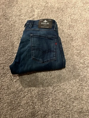 Mörkblå Replay jeans slim fit Anbass - Säljer ett par mörkblå jeans från Replay med klassisk femficksdesign och snygga slitningar. tillverkade i mjukt denimtyg. Perfekta till sneakers eller boots och riktigt sköna att bära hela dagen. Hör av dig vid frågor och funderingar 