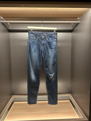 Replay blå jeans med raka ben - Säljer ett par klassiska blå jeans från Replay med raka ben och snygga slitningar. Jeansen har fem fickor, guldfärgad knapp och kontrastsömmar. Materialet är slitstarkt jeans och passformen är normal. Perfekta till en avslappnad stil.