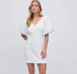 Vit klänning Gina Tricot - Supersöt vit kort klänning från Gina Tricot med puffiga korta ärmar och v-ringad hals. Klänningen har ett broderat, blommigt mönster i tyget och dragkedja i ryggen. Perfekt för sommarens alla tillfällen, riktigt fräsch och trendig look. Perfekt för student tex!!😍😍😍 aldrig använd endast testad! 