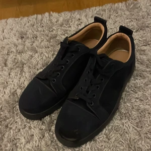 Marinblåa sneakers med röd sula - Marinblåa sneakers med snygg röd undersida och rund tå. Skorna har snörning och en stilren design med beige. Vilket ger en clean look. Perfekt för dig som gillar klassiska färger med en twist. Skorna är inte mycket använda men har ramlat med dem och skrapat upp en del av vänster framdel