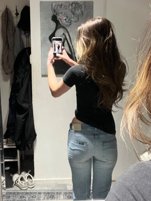 Ljusblå bootcut jeans från Lee - Säljer ett par ljusblå jeans från Lee med klassisk bootcut passform. Jeansen har låg midja, raka ben och snygga bakfickor med Lee-logga. Storlek W26 L31. 37cm midjemått och 77cm innerbenslängd 