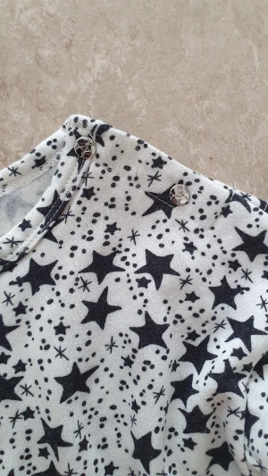 Klänning - Superfin klänning med svartvita stjärnor på toppen och en fluffig svart tyllkjol. Långärmad modell med rund hals och tryckknappar på axeln. Perfekt för dig som gillar coola mönster och mjuka material.