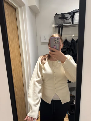 Krämvit kofta från Gina Tricot - Säljer en helt ny krämvit kofta från Gina Tricot. Koftan har långärmade, lite skulpturala ärmar och är stickad i mjukt material. Passformen är normal. 