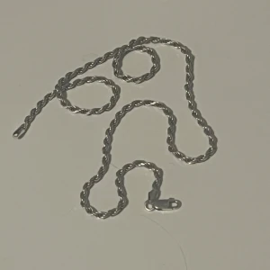 Snyggt tvinnat silverfärgat halsband - Stilrent halsband med tvinnad kedja i silverfärg. Kedjan har en klassisk karbinlås och passar perfekt för dig som gillar minimalistisk och clean stil. Längden är lagom för att bäras både ensam eller med andra smycken. Perfekt accessoar för att lyfta din look.