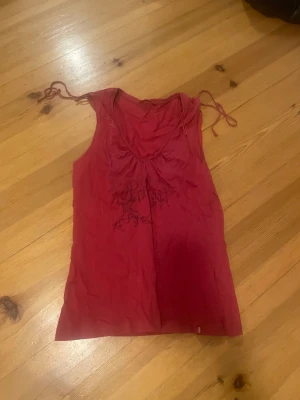 Röd linnetopp från edc by Esprit - Säljer en röd linnetopp från edc by Esprit i storlek L. Toppen har tunna axelband med knyt och ett tryck med texten 'Princess' framtill. Materialet är mjukt och lätt bomull, perfekt för varma dagar. Snygg v-ringning och avslappnad passform.