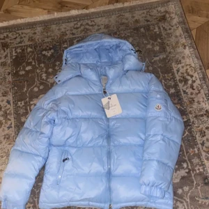 Ljusblå pufferjacka från Moncler - Säljer en snygg ljusblå pufferjacka från Moncler med huva och dragkedja framtill. Jackan har två sidofickor med dragkedja och Moncler-logga på ärmen. Perfekt för kalla dagar och riktigt stilren färg. Passar S och M eller 180cm och uppåt vid snabb affär kan pris diskuteras 