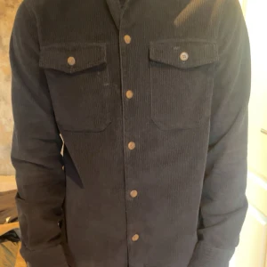 Marinblå Kappa från Jack & Jones - Marinblå/mörkblå kappa (ser svart ut på kameran bara). Aldrig använd, köpt för 600kr och säljer för halva priset. 