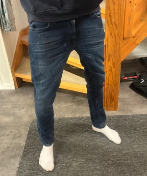 Mörkblå jeans från Nudie - Säljer ett par mörkblå jeans från Nudie med klassisk femficksdesign. Perfekta för dig som gillar en stilren och modern look. Modellen är 184cm 62kg
