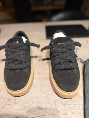 Svarta skor från Numeris i mocka - Kan sälja för 500 vid snabb affär. Svarta sneakers från Numeris med tjocka, fluffiga snören och beige platt sula. Skorna är tillverkade i mjuk mocka och har en rund tå. Snygg minimalistisk design som passar perfekt till streetwear. Levereras med dustbag från Numeris. Tillkommer ett par snören också 