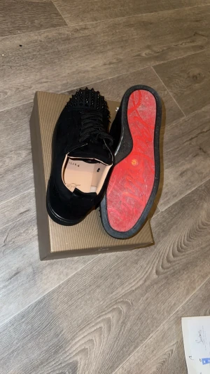 Svarta Christian Louboutin svarta med Spikar - Stilrena och exklusiva svarta sneakers från Christian Louboutin – perfekta för dig som vill sticka ut med lyxiga detaljer och ikonisk design! 🖤✨ Minimal användning, endast en gång, vilket gör dem i nästintill nyskick.  Snygg och bekväm passform som sitter riktigt bra på foten Karaktäristiska spikar som ger ett edgy och lyxigt uttryck.  Klassisk röd sula – en diskret men tydlig signatur Skickas samma dag eller dagen efter! Skicka PM vid frågor.