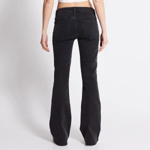Svarta bootcut jeans med låg midja - Snygga svarta jeans med bootcut passform och låg midja. Klassisk femficksdesign och svarta sömmar ger en clean look. Perfekta till sneakers eller boots för en cool vibe. Materialet är jeans och de är i ”full legnth”.