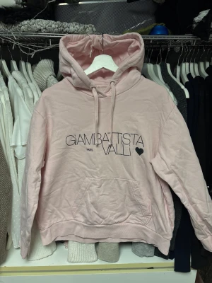 Ljusrosa hoodie Giambattista Valli - Säljer en ljusrosa hoodie från H&M med svart tryck och hjärtdetalj på bröstet. Tröjan har huva med snörning, stor magficka och ribbade muddar. 