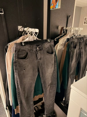 Grå/svarta ” Dsquared2 ” jeans - Säljer ett par grå jeans från Dsquared2 med slitna detaljer och broderad logga på bakfickan. Snyggt tvättade för en cool, avslappnad look. Byxorna är i mycket bra skick! 
