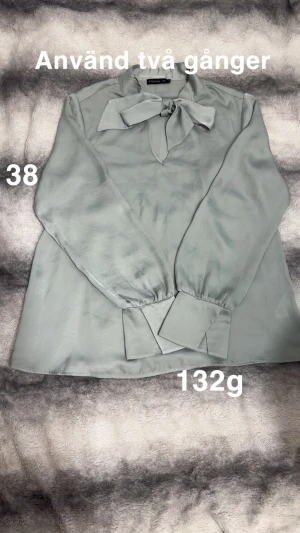 Ljusgrön blus med rosett från Stockh LM - Supersnygg ljusgrön blus från Stockholm LM med lång ärm och breda manschetter. Blusen har en elegant rosett vid halsen och är gjord i ett glansigt, silkesliknande material som känns lyxigt och trendigt.🌸 Använd två gånger. Storlek 38