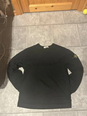 Svart långärmad tröja Stone Island - Svart långärmad tröja från Stone Island med en patch på vänster axel den den är storlek M och äkta du kan se den är äkta ifall du skannar qr koden eller slår in koden
