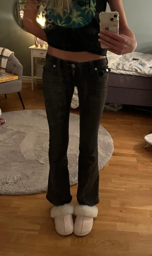 True Religion Joey Low Rise Flare jeans - Svarta jeans från True Religion, modell Joey Low Rise Flare. Snygg och väldigt låg midja även utsvängda ben med bootcut-stil. Klassiska silverfärgade knappar och detaljerade bakfickor med broderade sömmar. Jeansen är gjorda i stretchig denim för skön passform. Jag säljer jeansen då de har blivit för korta då jag är 174 cm lång. Innerbens längden är 80cm. Midjemått 74 cm.