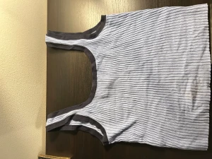 Ribbad ljusblå linnetopp från Divided - Säljer en ribbad ljusblå linnetopp från Divided med mörkblå kantband. Toppen är ärmlös och har en slim passform, perfekt för varma dagar. Enkel och stilren design som funkar till många olika looks.