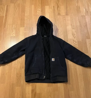 14-16yr/Xs Carhartt jacka  - Säljer denna snygga carhartt jackan som man kan ha till vintern och början på våren. Den är svart och i relativt bra skick, bara lite smått skadad på ena ärmen, samtidigt som den har den slitna looken som carhartt jackor ska ha.