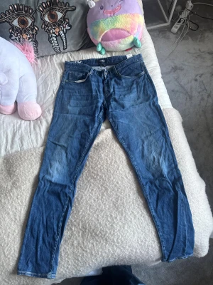 Blå Dondup jeans - Säljer ett par blå jeans från Dondup, limited edition, med klassisk femficksdesign och smal passform. Jeansen är tillverkade i italienskt denim och har snygga detaljer som kontrastsömmar och knappgylf. 