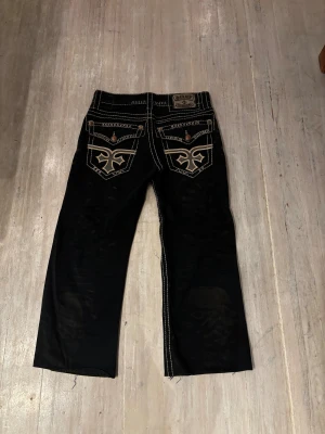Olimp Dorian Fit Bootcut jeans 30/32 - RARE Svarta jeans från Olimp med bootcut passform och Dorian Fit. Snygga kontrastsömmar i vitt, detaljerade bakfickor med broderad logga och metallknappar med stjärnmotiv🔥🔥. Materialet är klassisk jeans och midjan är normal. uppsydda. Perfekt för dig som gillar statement-jeans🙏