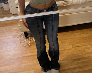 Mörkblå bootcut jeans med låg midja - Snygga mörkblå jeans med bootcut och låg midja. Jeansen har klassiska fem fickor, kontrastsömmar och en lätt tvättad look framtill och baktill. Passformen är figurnära upptill och släpper vid benen för en schysst siluett. Perfekt för dig som gillar en trendig och avslappnad stil.