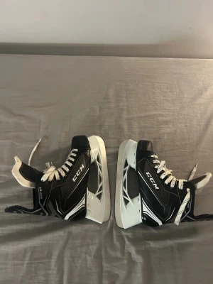 Svarta CCM Tacks skridskor strl 35 - Säljer ett par svarta CCM Tacks skridskor med vita detaljer och snörning. Skridskorna har en sportig design med robust plastsula och metallblad. Perfekt för dig som vill ha snygga och bekväma skridskor på isen. Märke och storlek syns tydligt på plösen. Ps frakt ingår ej