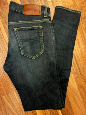 Mörkblå skinny jeans från Tiger of sweden - Snygga mörkblå jeans från Tiger Of Sweden med klassisk femficksdesign och kontrastsömmar. Modellen är skinny med smal passform och har en läderpatch med logga bak i midjan. Perfekt för dig som gillar stilrena och tajta jeans.