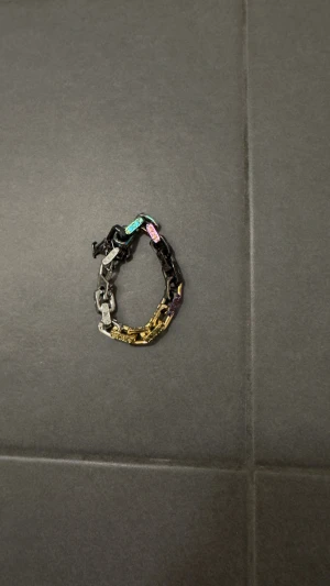 Louis Vuitton färgglatt kedjearmband - Unikt armband från Louis Vuitton med chunky kedjelänkar i flera färger: svart, silver, guld och inslag av blått, rosa och lila. Kommer med originalpåse och box. Perfekt statement piece för dig som gillar lyx och färg. Pris kan diskuteras 