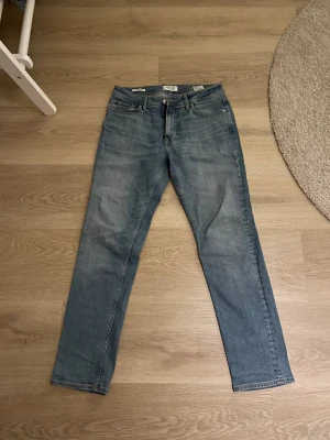 Ljusblå jeans - Snygga ljusblå jeans från Jack & Jones, modell Regular Clark. Klassisk femficksdesign med raka ben och normal passform. Jeansen har en stilren look med subtila slitningar. Hör av er vid frågor!