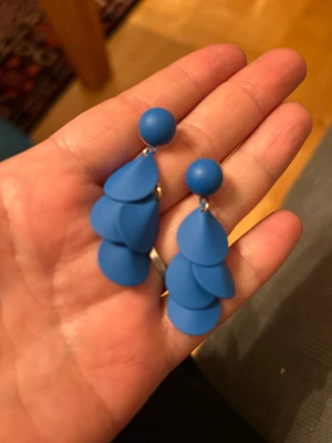 Blå örhängen med droppar - Säljer ett par coola blå örhängen med flera droppformade hängen i lager på varje örhänge. De har en rund blå plupp upptill och hängande droppar som ger ett snyggt och trendigt uttryck. Perfekt för dig som vill sticka ut med färg och form!