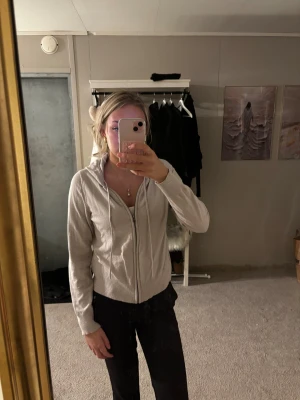Beige hoodie med dragkedja - Beige hoodie med dragkedja och huva. Tröjan har långa ärmar, ribbade muddar och en enkel, clean look. Perfekt för lager-på-lager och chill dagar. 